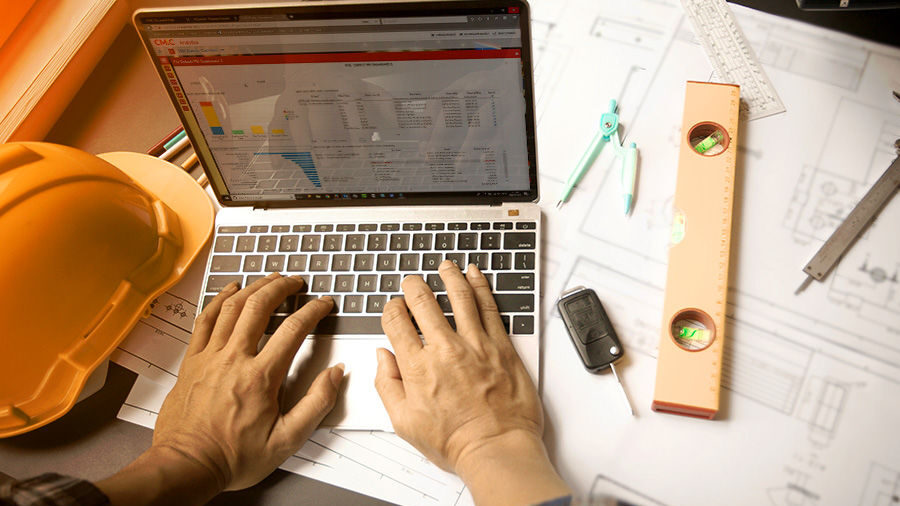 A man typing on his computer using a construction management software