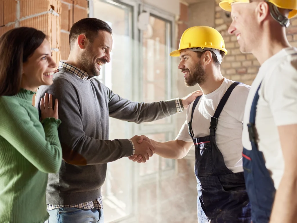 A happy couple shaking hands with home builders