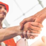 A contractor and owner handshaking after signing a Guaranteed Maximum Price (GMP) Contract