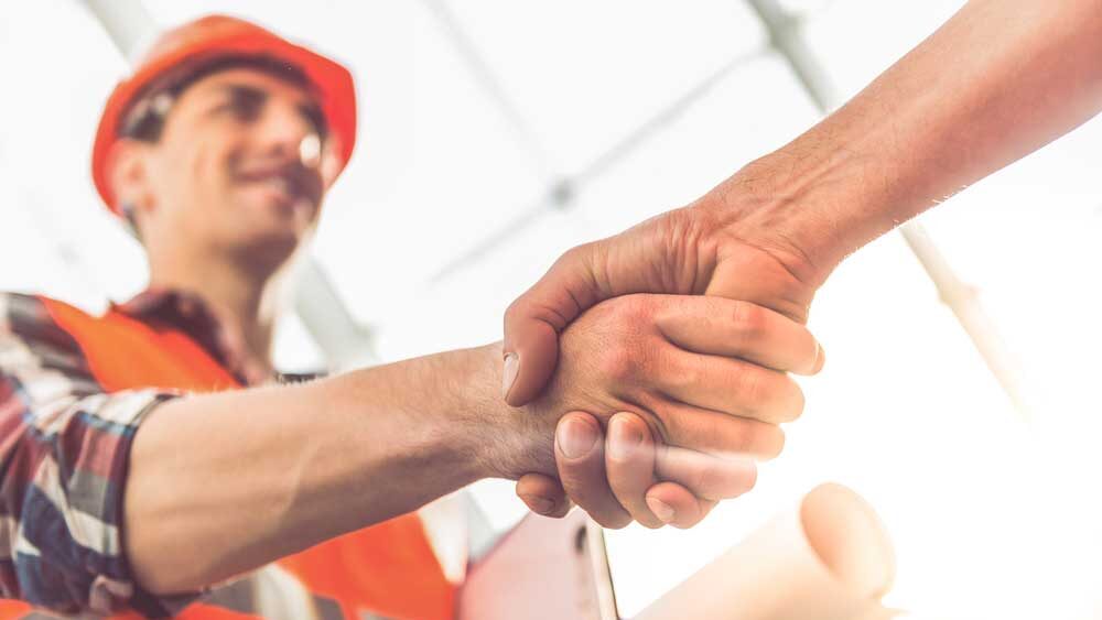 A contractor and owner handshaking after signing a Guaranteed Maximum Price (GMP) Contract